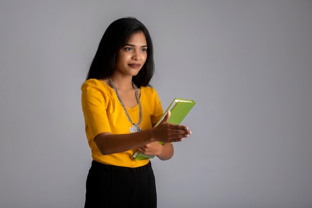 Muito jovem posando com o livro na parede cinza