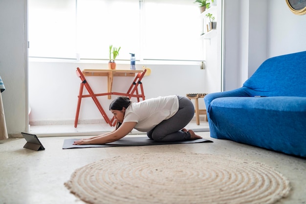 muito jovem praticando exercícios e ioga em sua sala de estar com um gato preto