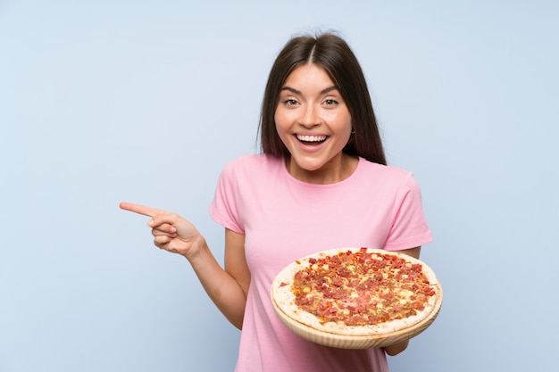 Foto muito jovem, segurando uma pizza surpreendeu e apontando o dedo para o lado