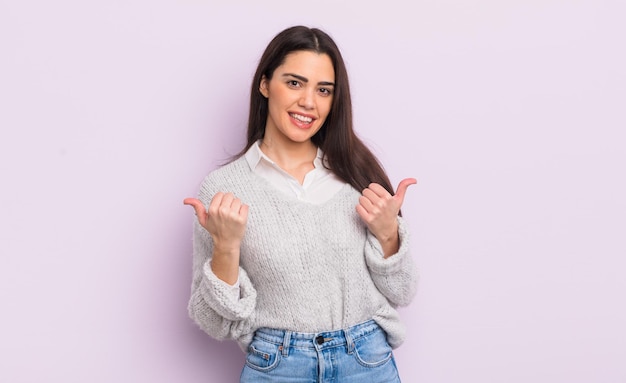 Muito jovem sorrindo alegremente e parecendo feliz sentindo-se despreocupada e positiva com os dois polegares para cima