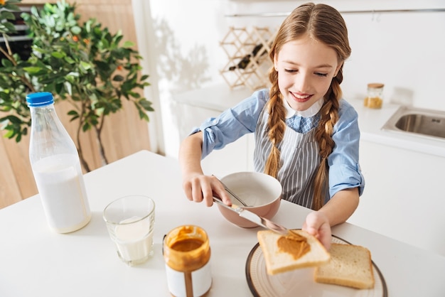 Muito perfeito. Envolvendo uma garota linda e adorável cozinhando o café da manhã para ela e seu irmão, enquanto usava um avental e ficava de pé à mesa na cozinha