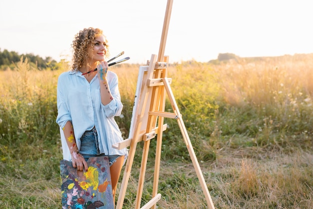 Muito talentosa pintora pintando no cavalete, fazendo desenhos coloridos, criando paisagem marinha. Bela artista feminina pintando com tintas em aquarela. Conceito de criatividade e imaginação.