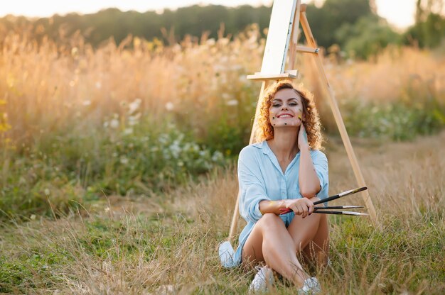 Muito talentosa pintora pintando no cavalete, fazendo desenhos coloridos, criando paisagem marinha. Bela artista feminina pintando com tintas em aquarela. Conceito de criatividade e imaginação.