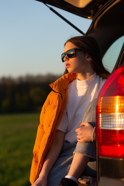 Muito triste adolescente com óculos de sol sentado sozinho em um porta-malas