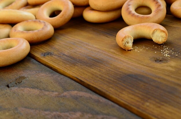 Muitos bagels amarelos frescos encontram-se na superfície da madeira escura velha