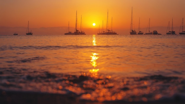 Muitos barcos na superfície do oceano durante o nascer do sol