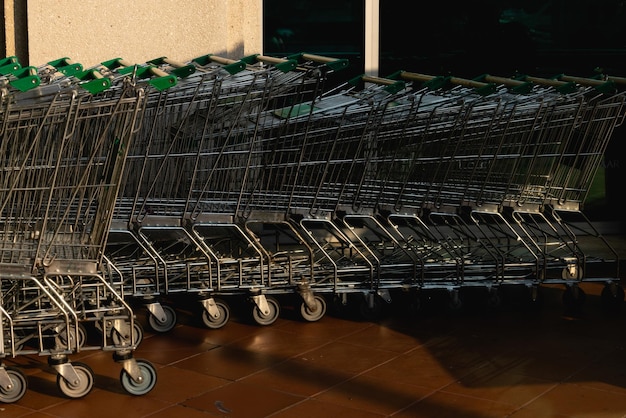 Muitos carrinhos de compras de metal em um estacionamento perto do supermercado ao ar livre Conceito de compras