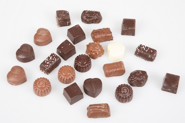 Muitos chocolates escuros e de leite finos em diferentes formas de bombons em barra de chocolate em vista superior em fundo branco