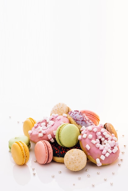 Muitos donuts de macarons multicoloridos com diferentes sabores macaroons de sobremesa e donuts em uma parte traseira branca