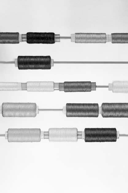 Muitos enrolamentos de fios de vários tamanhos e cores dispostos em fileiras em hastes finas paralelas