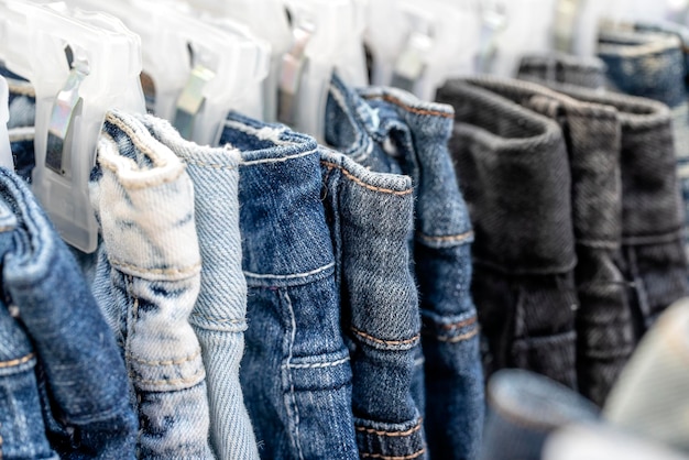 Muitos jeans azuis em cabides à venda no mercado de rua na tailândia fecham