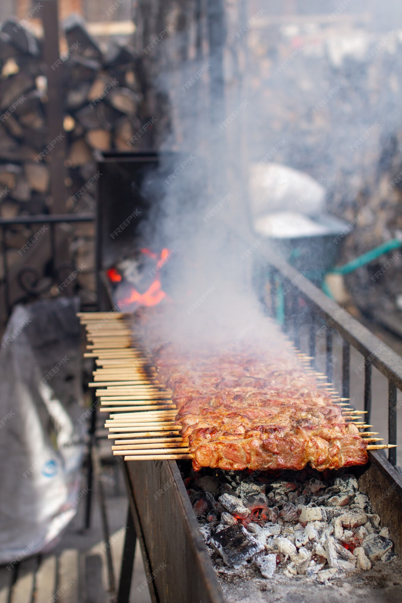 Muitos kebabs seguidos na grelha. espetadas amarradas em espetos de madeira  em um café de rua. o processo de cozinhar kebabs com muita fumaça.