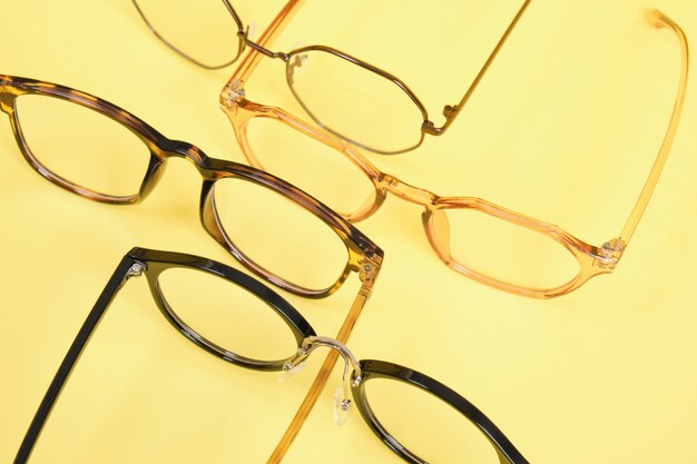 Muitos óculos modernos da moda para correção da visão em um espaço de cópia de fundo amarelo