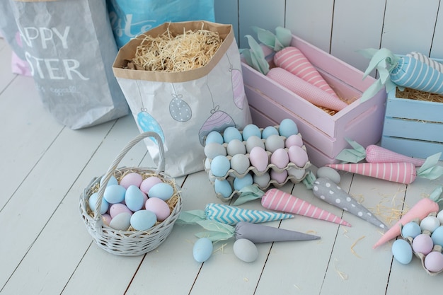 Muitos ovos de Páscoa coloridos e cestas de cenouras na decoração do quarto de Páscoa do piso de madeira