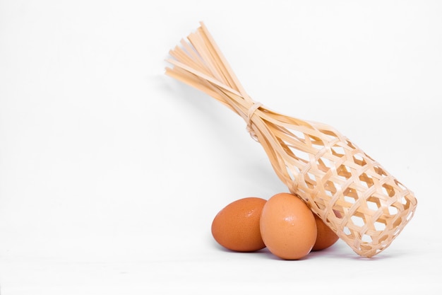 Muitos ovos (frango) com cesta de madeira isolado no fundo branco