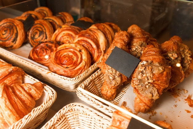 Muitos pães e croissants em uma prateleira de uma padaria