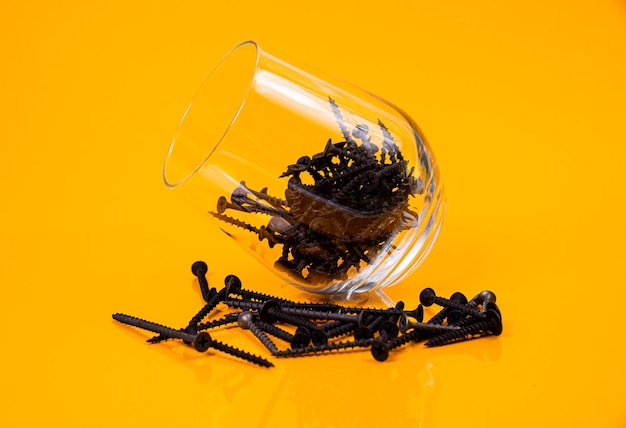Foto muitos parafusos de auto-tapeamento de metal feitos de aço em um vidro em frasco de balde parafuso de auto- tapeamento para metal para ferro parafuse de auto-tapeamento cromado em um fundo amarelo laranja