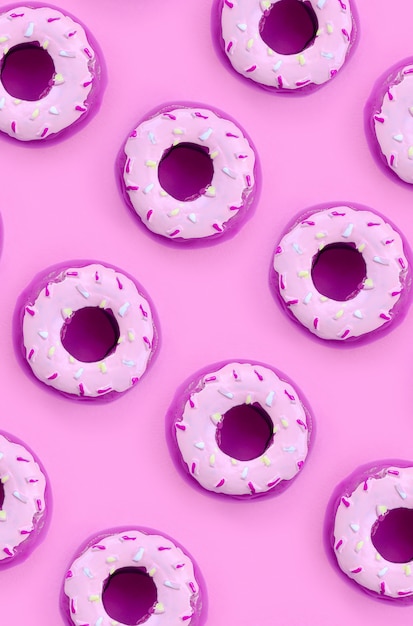 Muitos pequenos donuts de plástico encontra-se em um fundo colorido pastel