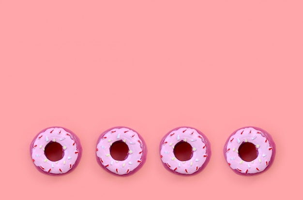 Muitos pequenos donuts de plástico encontra-se em um fundo colorido pastel