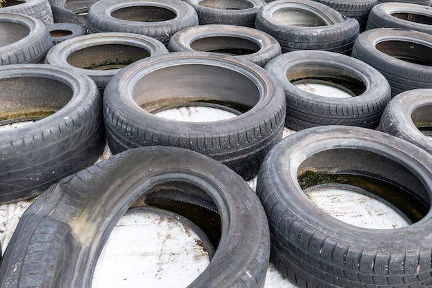 Muitos pneus de carros usados velhos fecham em fundo branco