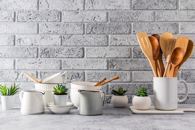 Muitos pratos leves e elegantes diferentes na bancada da cozinha no interior de uma cozinha moderna Parede de tijolos cinza Um espaço de cópia