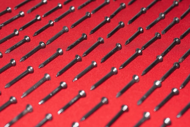 Muitos pregos de aço preto sobre fundo vermelho dispostos na diagonal perfeitamente conceito de perfeccionismo