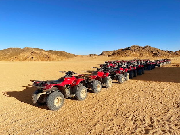 Muitos quadriciclos vermelhos estão parados no deserto sem pessoas estacionamento quad