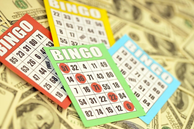 Foto muitos tabuleiros de bingo ou cartas de baralho para ganhar fichas e grande quantidade de notas de dólar clássico americano ou canadense de cinco a cinco cartões de bingo em dinheiro