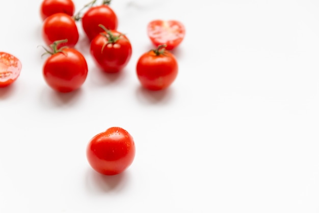 Muitos tomates cereja frescos espalhados aleatoriamente em um fundo branco