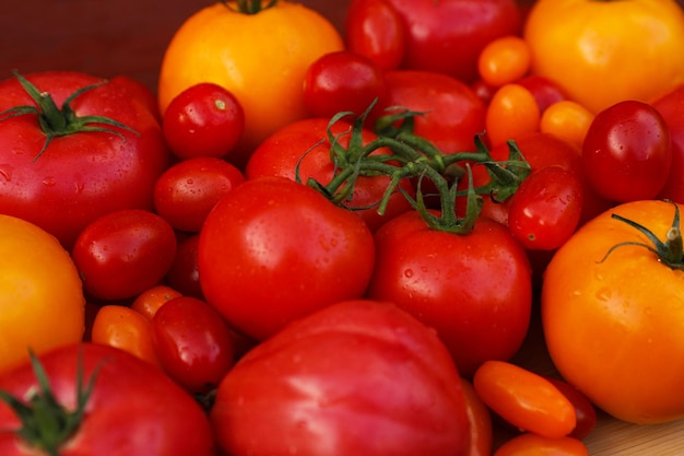 Muitos tomates frescos na superfície de madeira closeup