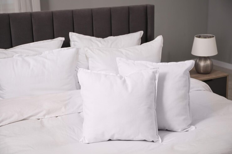 Foto muitos travesseiros e edredons brancos e macios na cama dentro de casa