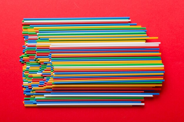 Muitos tubos de plástico multicoloridos para coquetel na vista superior de fundo colorido