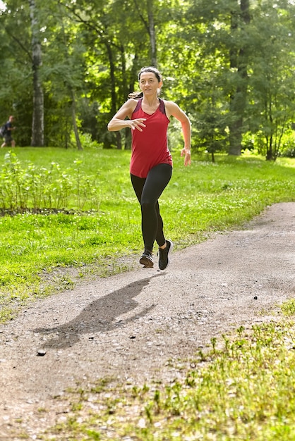 Foto mujer de 40 años corre en parque público.