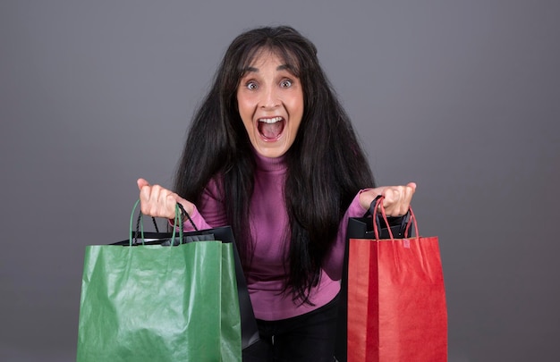 Mujer de unos 40 años gritando con bolsas de compras en las manos