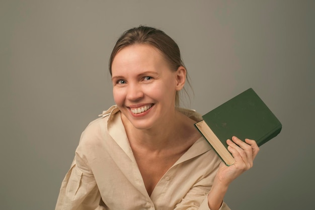 Mujer de 40 años con un libro sobre un fondo claro