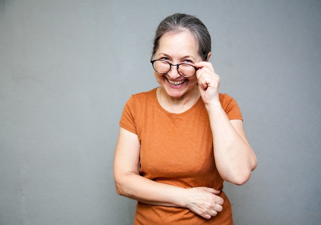 Mujer de 55 años con gafas se ríe y mira a la cámara