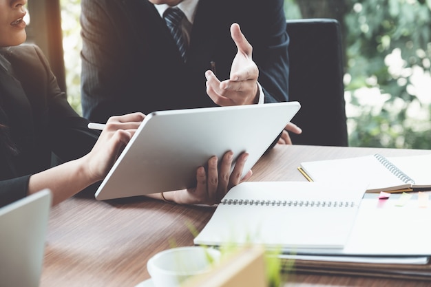 Mujer y abogados de negocios que discuten y que usan la tableta digital en el escritorio de madera en oficina. Derecho, servicios jurídicos, asesoramiento, concepto de justicia.