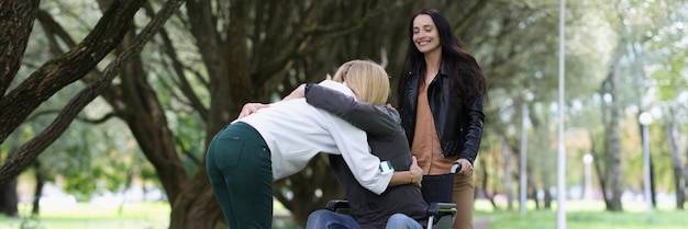 Foto la mujer abraza al hombre en silla de ruedas en el concepto de apoyo al parque y rehabilitación de personas