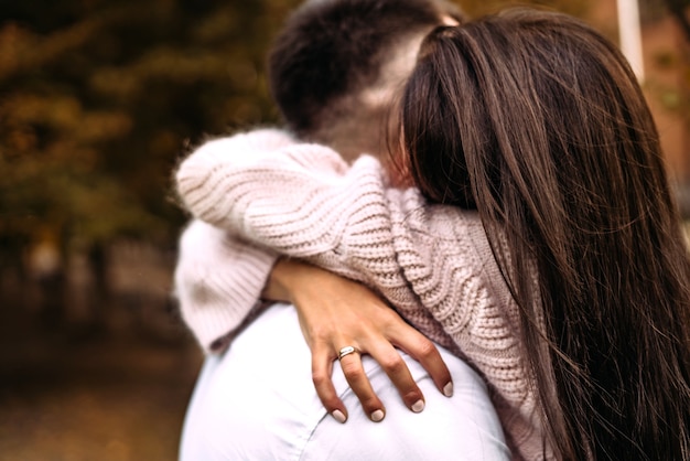 Una mujer abraza a su amado hombre muy fuerte en el parque en el bosque de otoño otoño relación amorosa