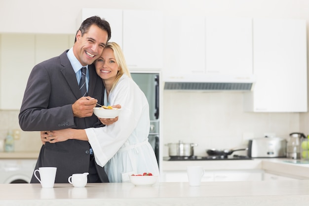 Mujer abrazando al hombre bien vestido en la cocina