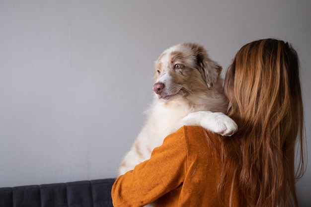 Mujer abrazando hermoso perro de cachorro de merle rojo lindo pequeño pastor australiano. Mejores amigos. Amor y amistad entre humanos y animales. cuatro meses.