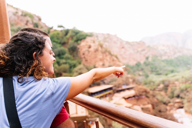 Foto una mujer abrazando a un hombre señalando el horizonte frente a un paisaje árido con pequeñas casas. cascadas de ouzoud en marruecos