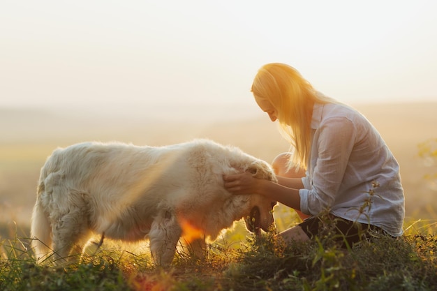 mujer abrazando a un lindo perro blanco en la pradera de verano