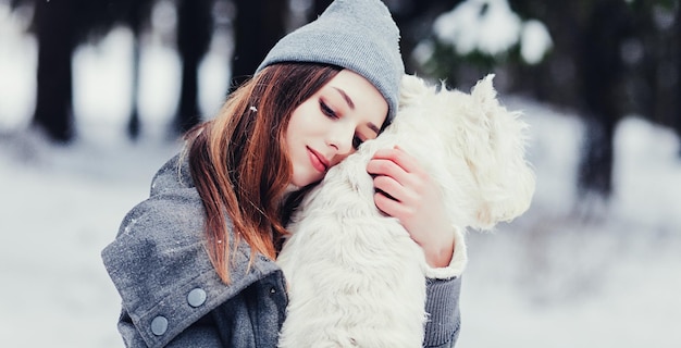 Mujer abrazando perro terrier blanco