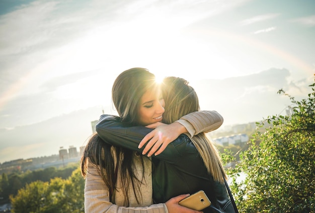 Foto mujer abrazando a su amiga contra el cielo