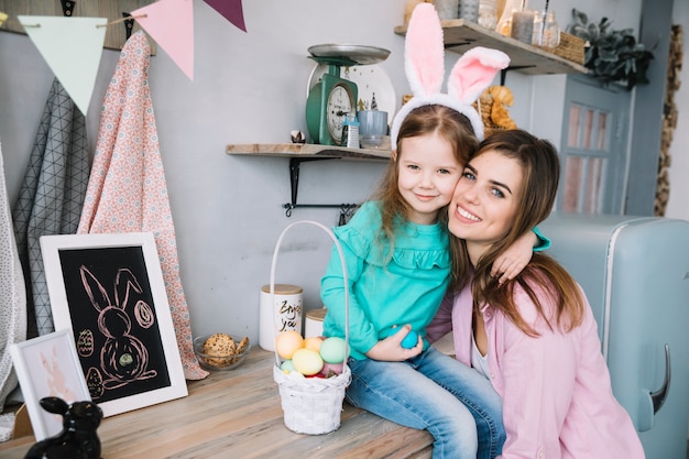 Foto mujer abrazando a su hija en orejas de conejo