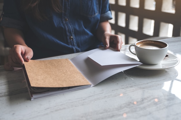 Mujer abre un libro con una taza de café sobre la mesa en la cafetería moderna