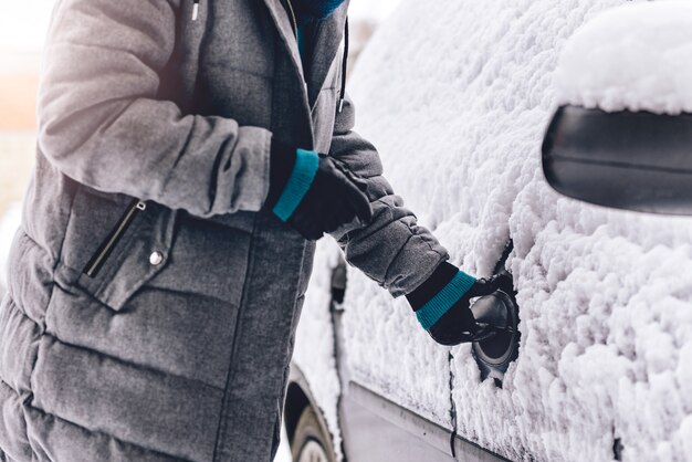 Mujer abriendo coche cubierto de nieve