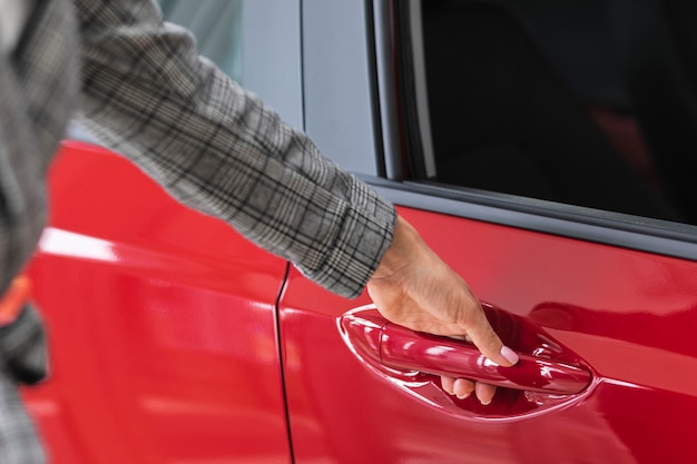 Mujer abriendo la puerta de un auto rojo