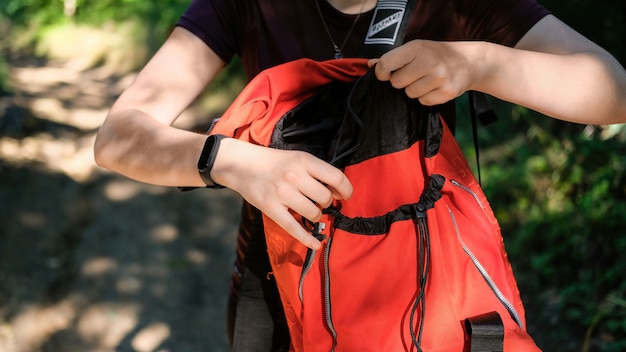 Mujer abriendo su mochila de senderismo naranja en un bosque